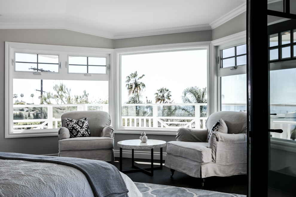 Inspiration for a large beach style master bedroom in San Diego with grey walls, dark hardwood flooring, a standard fireplace and a stone fireplace surround.