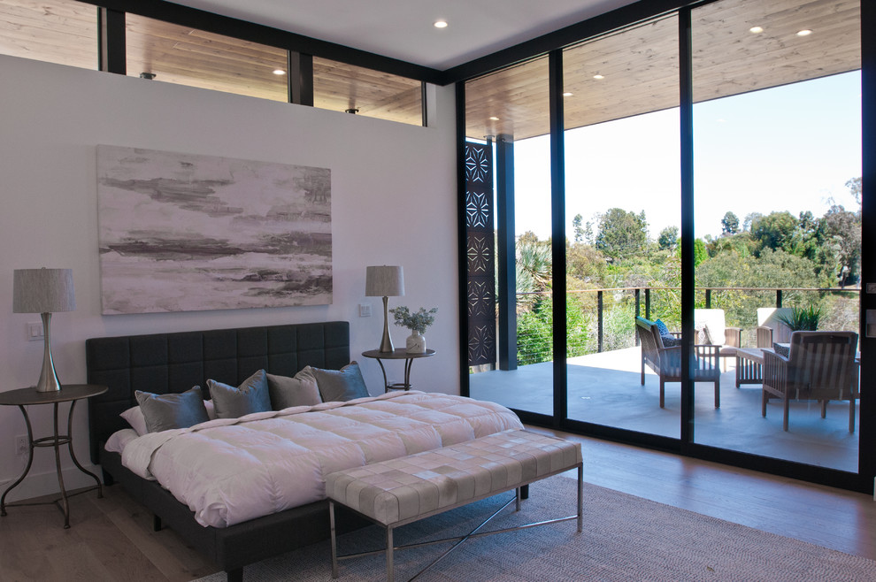 Imagen de dormitorio principal minimalista grande sin chimenea con paredes blancas, suelo de madera en tonos medios y suelo beige