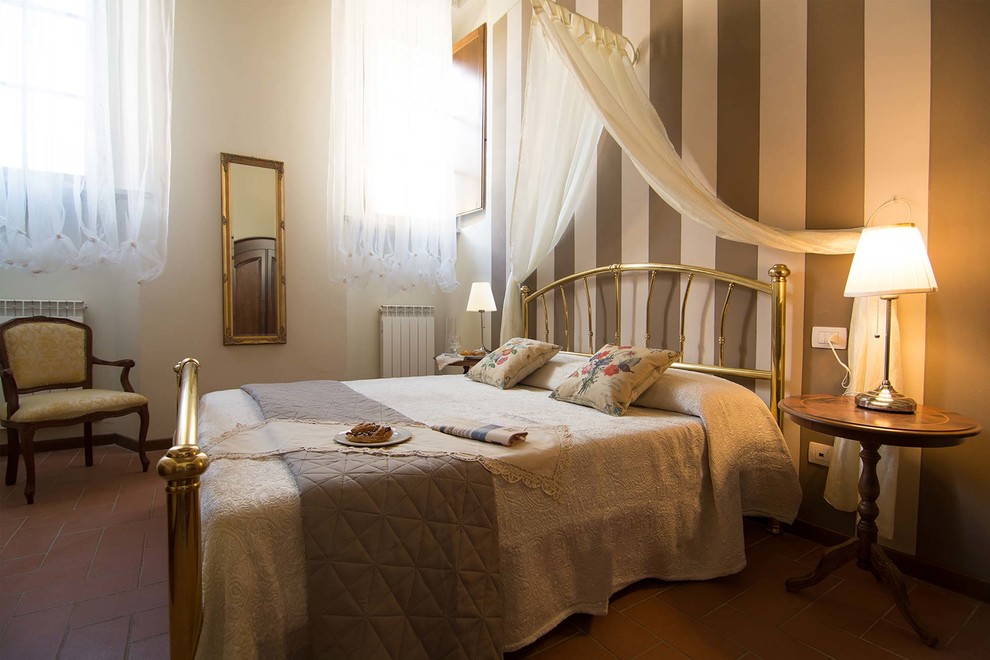 На фото: большая хозяйская спальня в классическом стиле с белыми стенами и полом из терракотовой плитки