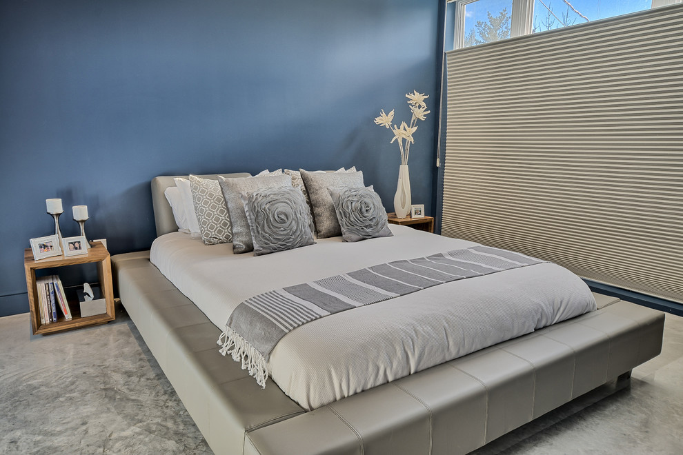 モントリオールにある中くらいなコンテンポラリースタイルのおしゃれな主寝室 (青い壁、コンクリートの床、暖炉なし)