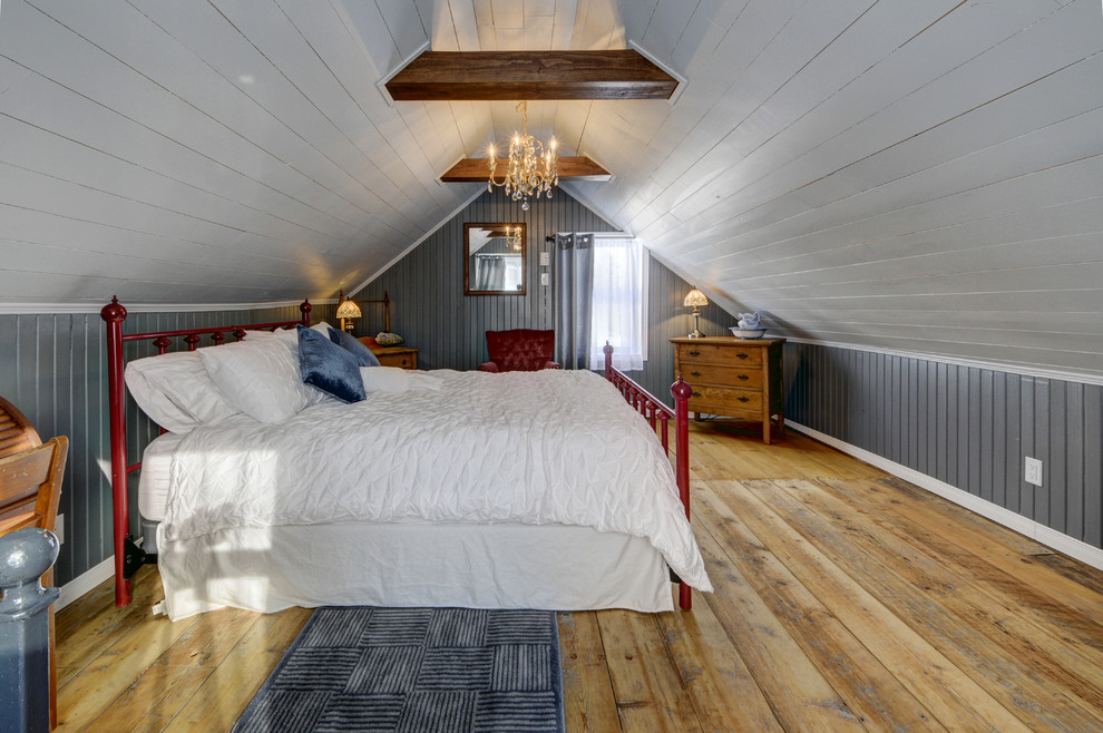 Diseño de dormitorio principal rural grande con paredes grises y suelo de madera clara