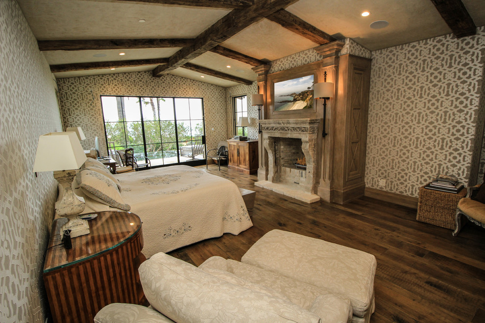 Immagine di una camera da letto stile rurale con parquet scuro, camino classico e cornice del camino in pietra