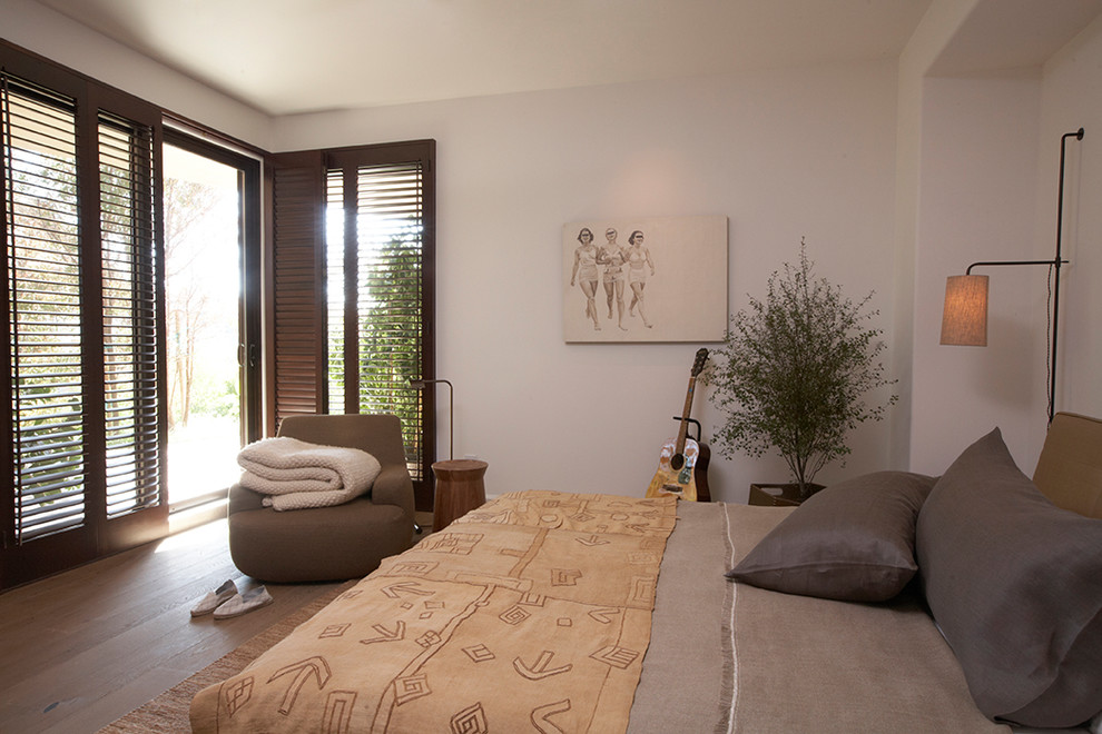 Imagen de habitación de invitados contemporánea de tamaño medio con paredes blancas, suelo de madera clara y suelo marrón