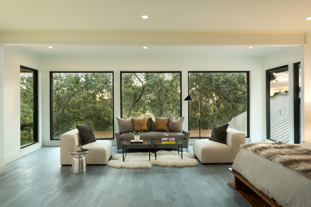 Geräumiges Modernes Hauptschlafzimmer mit hellem Holzboden und Kaminumrandung aus Stein in Austin