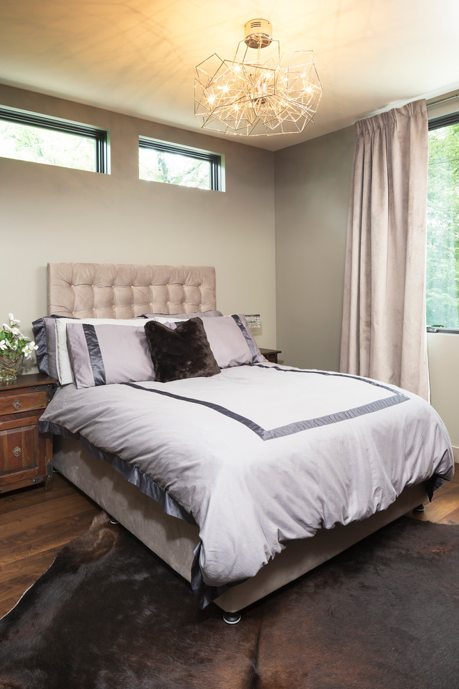Modelo de habitación de invitados moderna pequeña con paredes beige y suelo de madera en tonos medios