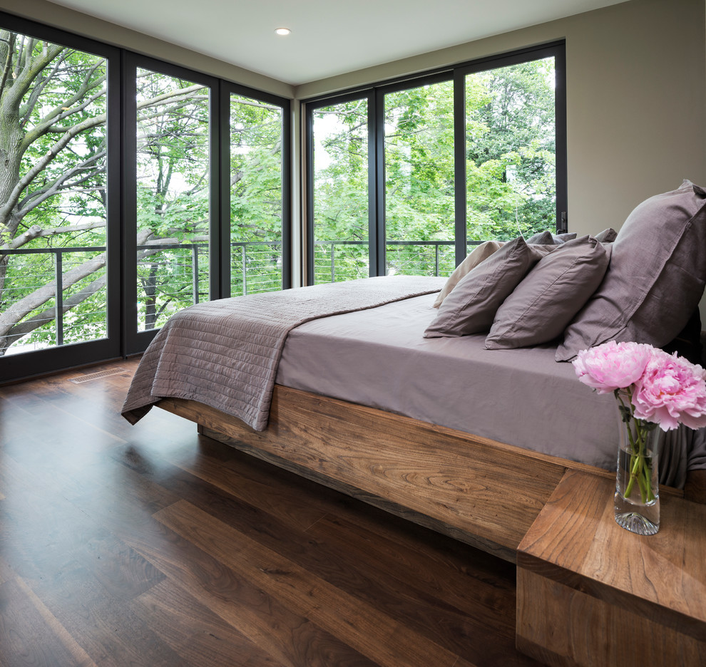 Modelo de dormitorio principal moderno pequeño con paredes beige y suelo de madera en tonos medios