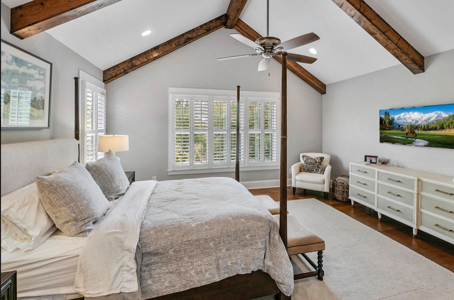 Exemple d'une grande chambre parentale chic avec un mur gris, un sol en bois brun, un sol marron et un plafond voûté.