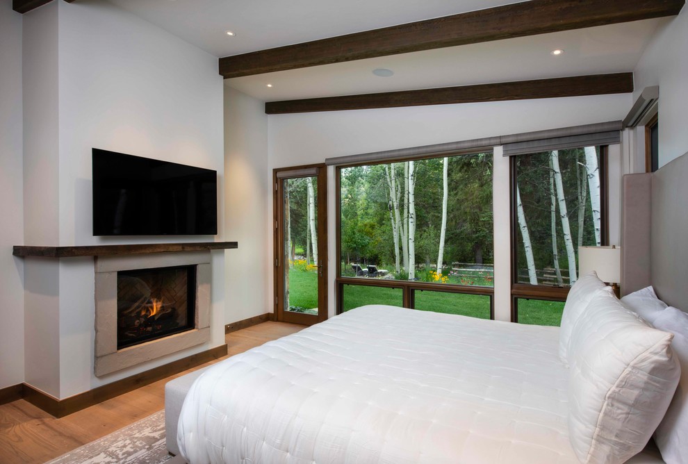 Foto di una camera da letto stile rurale con pareti bianche, pavimento in legno massello medio, camino classico e pavimento marrone