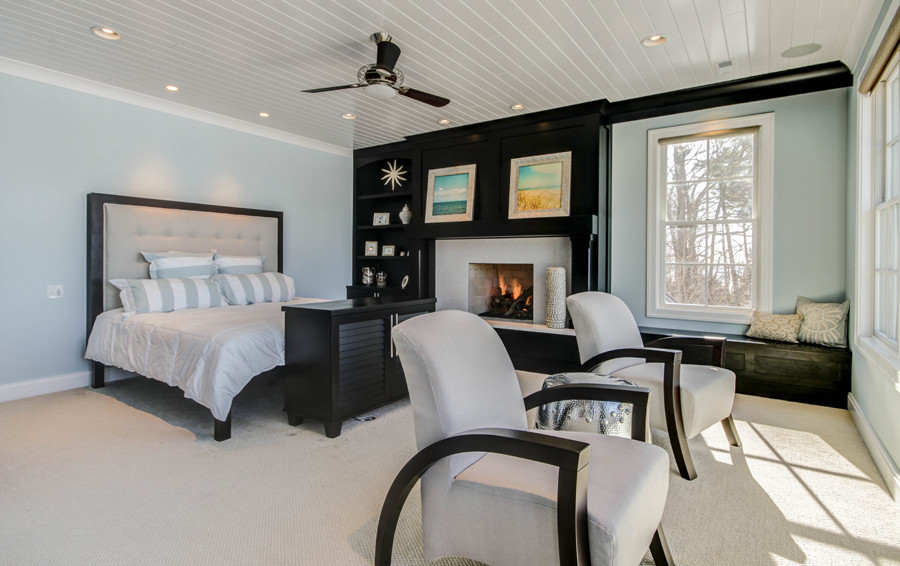 グランドラピッズにある広いコンテンポラリースタイルのおしゃれな主寝室 (青い壁、カーペット敷き、標準型暖炉、木材の暖炉まわり)