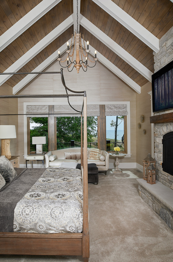 Maritimes Hauptschlafzimmer mit beiger Wandfarbe, Teppichboden, Kaminumrandung aus Stein und beigem Boden in Grand Rapids