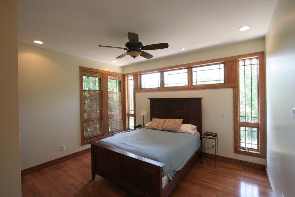 Idée de décoration pour une chambre d'amis craftsman de taille moyenne avec un mur beige et un sol en bois brun.