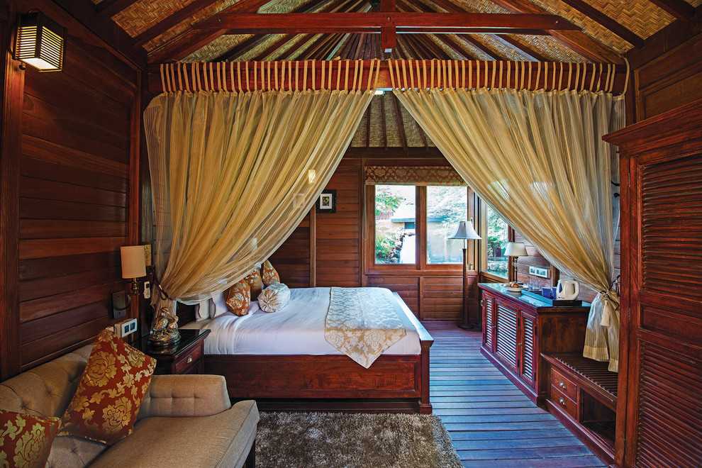 Immagine di una grande camera da letto tropicale con parquet scuro
