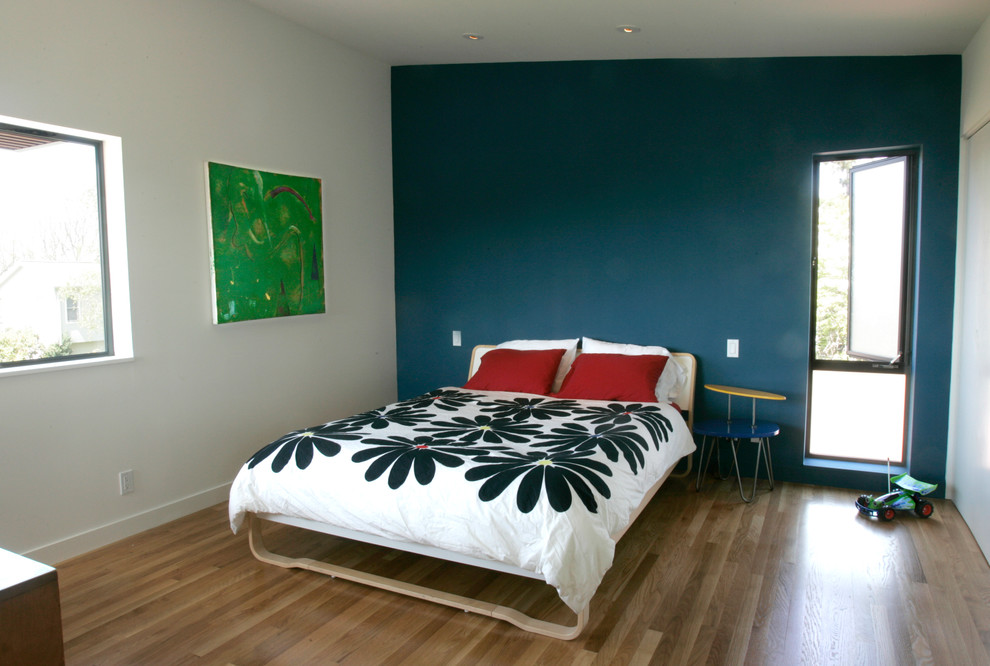Imagen de dormitorio actual sin chimenea con paredes azules y suelo de madera clara