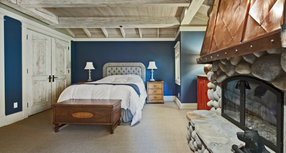 Foto de habitación de invitados costera de tamaño medio con paredes azules, moqueta, todas las chimeneas y marco de chimenea de piedra