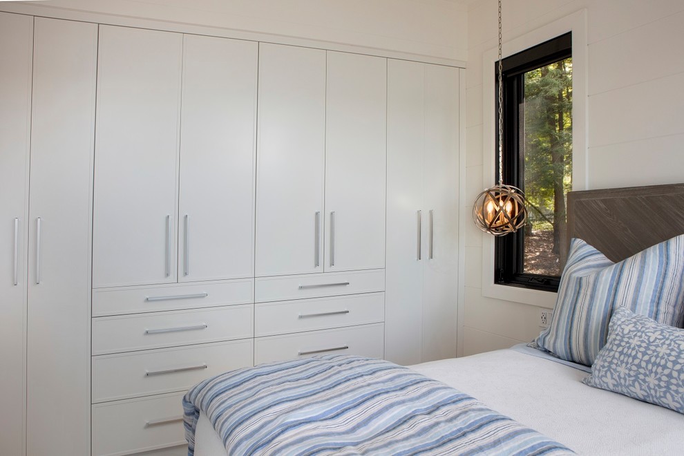 Cette image montre une chambre d'amis design de taille moyenne avec un mur blanc, parquet clair et un sol marron.