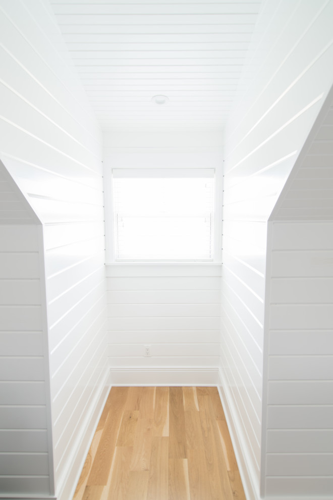 Kleines Uriges Hauptschlafzimmer mit weißer Wandfarbe, braunem Holzboden, beigem Boden, Holzdielendecke und Holzdielenwänden in Chicago