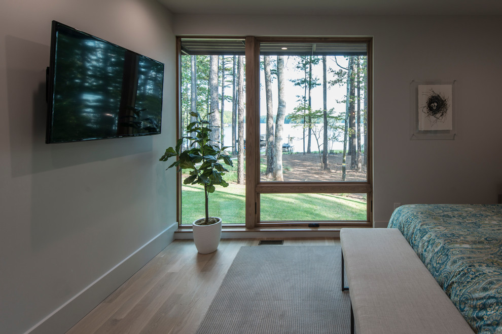 Diseño de habitación de invitados moderna de tamaño medio sin chimenea con paredes grises y suelo de madera clara