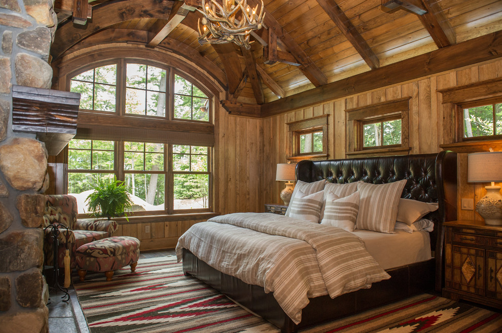 Photo of a rustic master bedroom in Toronto with medium hardwood flooring, a standard fireplace and a stone fireplace surround.