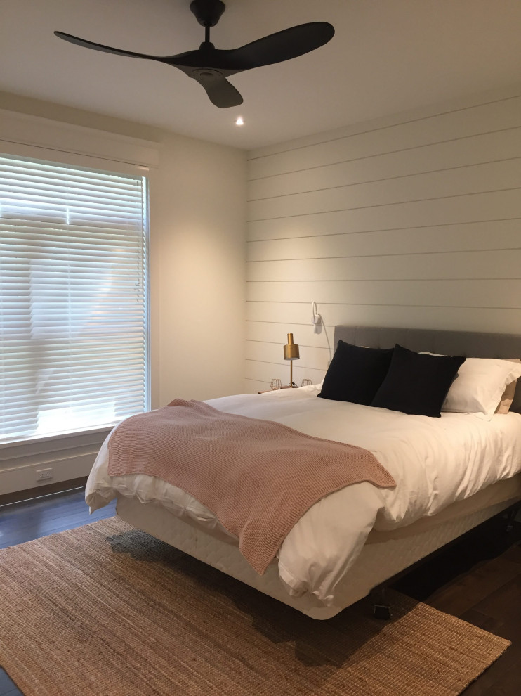 Modelo de habitación de invitados de estilo americano con suelo de madera oscura y machihembrado