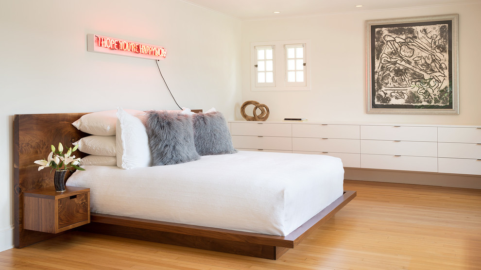 Ispirazione per una camera da letto design con pareti bianche e pavimento in legno massello medio