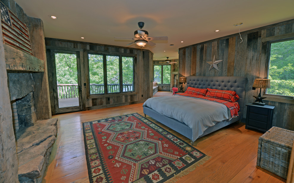 Bild på ett rustikt sovrum, med mellanmörkt trägolv, en standard öppen spis och en spiselkrans i sten