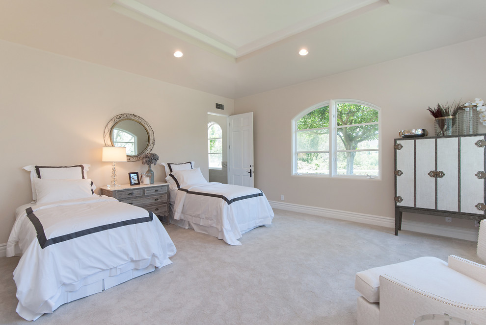 This is an example of a large mediterranean guest bedroom in Los Angeles with beige walls, carpet and no fireplace.