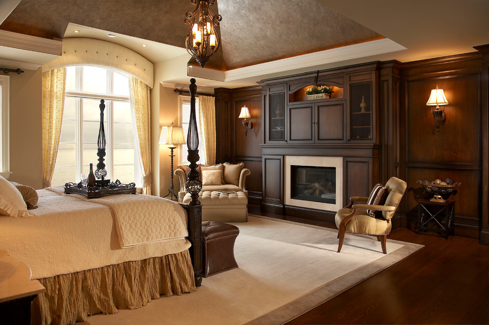 Foto de dormitorio principal tradicional grande con paredes beige, suelo de madera oscura, todas las chimeneas y marco de chimenea de madera