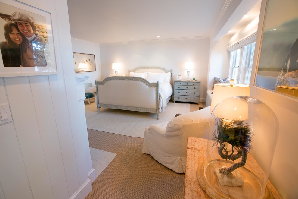 Imagen de dormitorio principal costero grande con paredes blancas, moqueta, todas las chimeneas y marco de chimenea de piedra