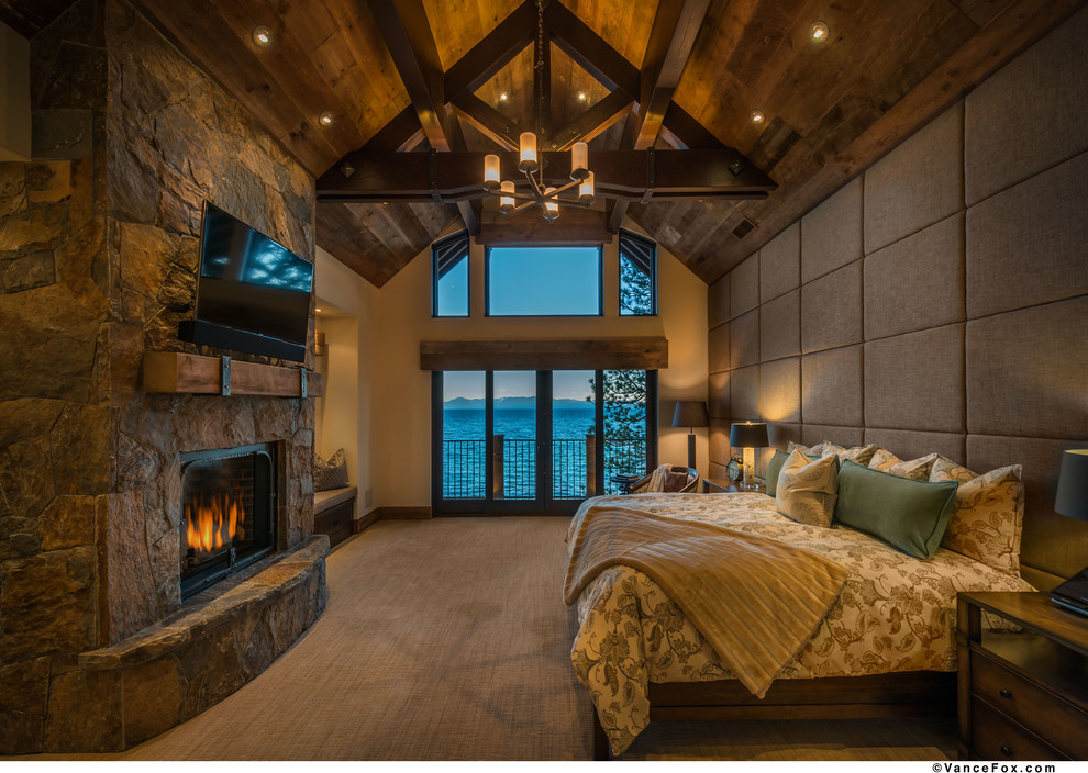 На фото: спальня в стиле модернизм с ковровым покрытием и фасадом камина из камня с