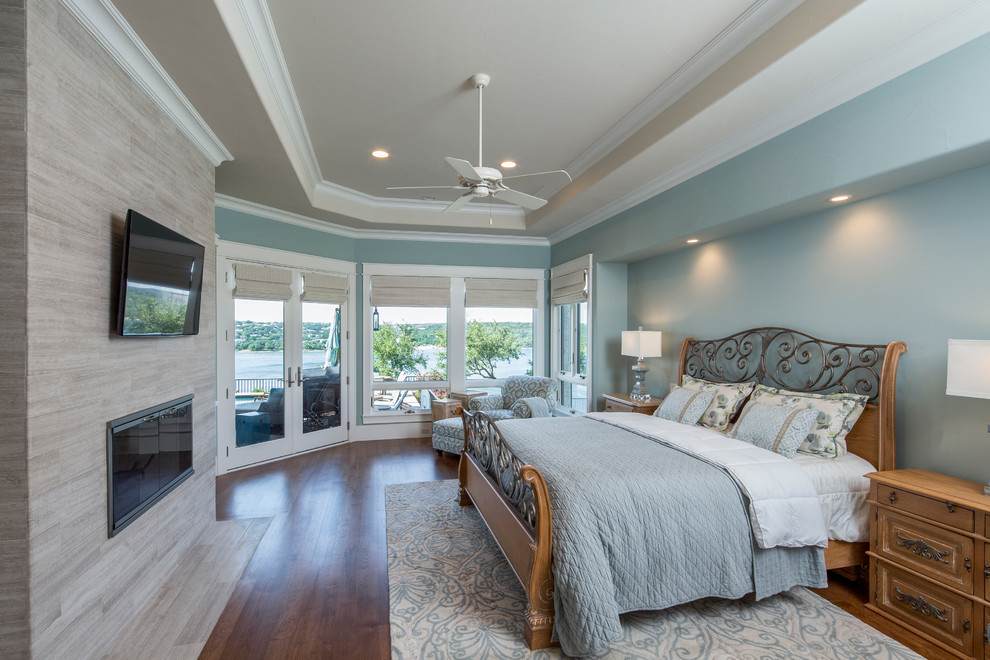 Foto de dormitorio principal de estilo americano extra grande con paredes azules, suelo de madera en tonos medios, todas las chimeneas y marco de chimenea de baldosas y/o azulejos