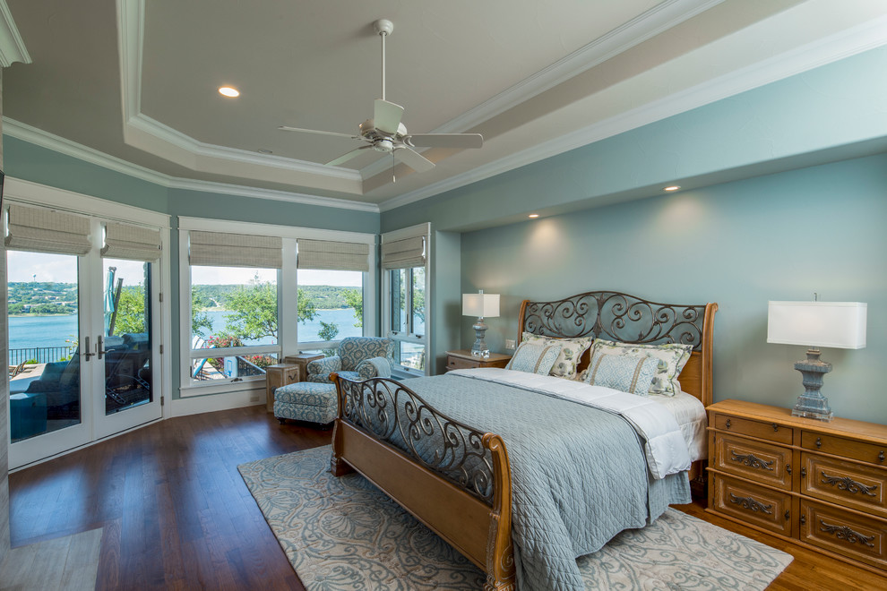 На фото: огромная хозяйская спальня в стиле кантри с синими стенами, паркетным полом среднего тона, стандартным камином и фасадом камина из плитки