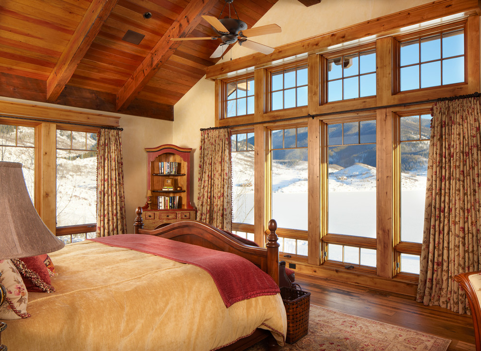 Example of a large mountain style master dark wood floor and brown floor bedroom design in Denver with beige walls
