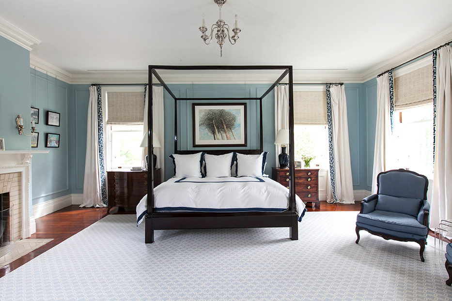 Modelo de habitación de invitados tradicional renovada grande con paredes azules, suelo de madera oscura, todas las chimeneas y marco de chimenea de ladrillo