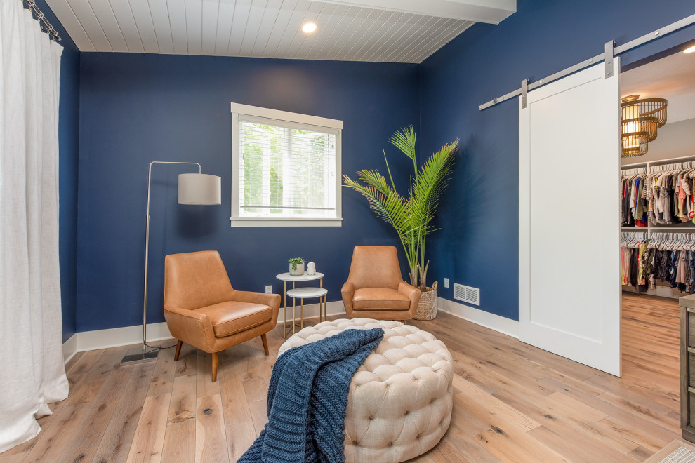 Cette image montre une grande chambre parentale marine avec un mur bleu, un sol en bois brun et un plafond en lambris de bois.