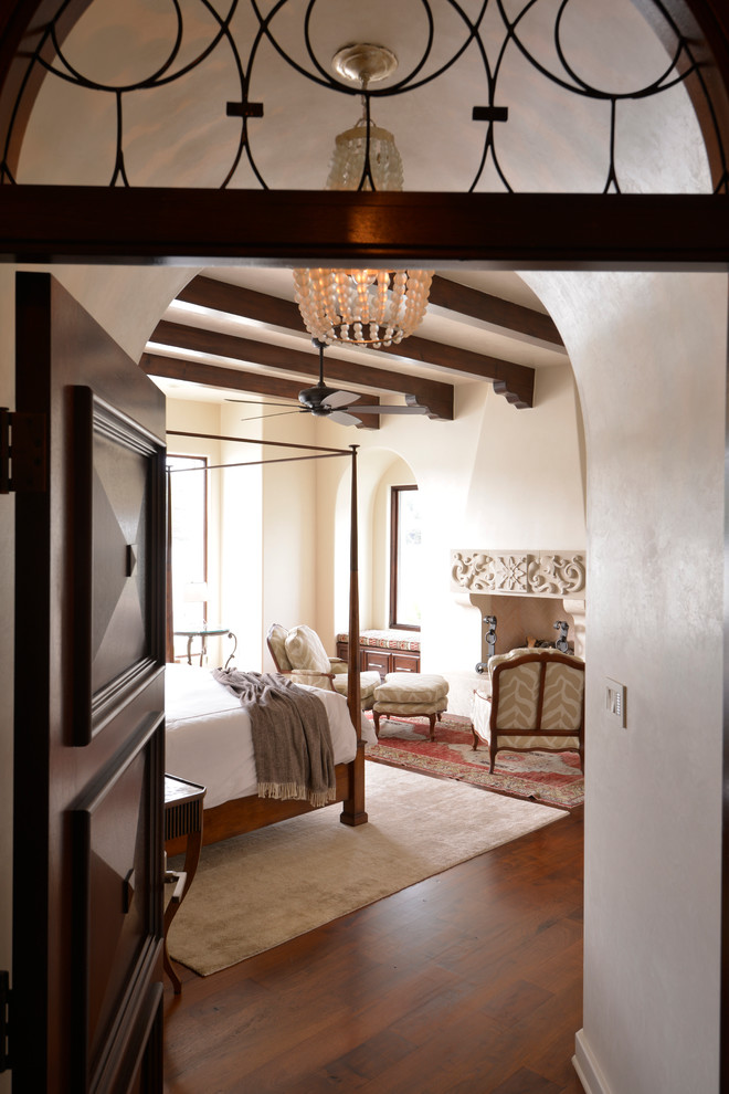 Großes Klassisches Hauptschlafzimmer mit weißer Wandfarbe, braunem Holzboden, Kamin und verputzter Kaminumrandung in Austin