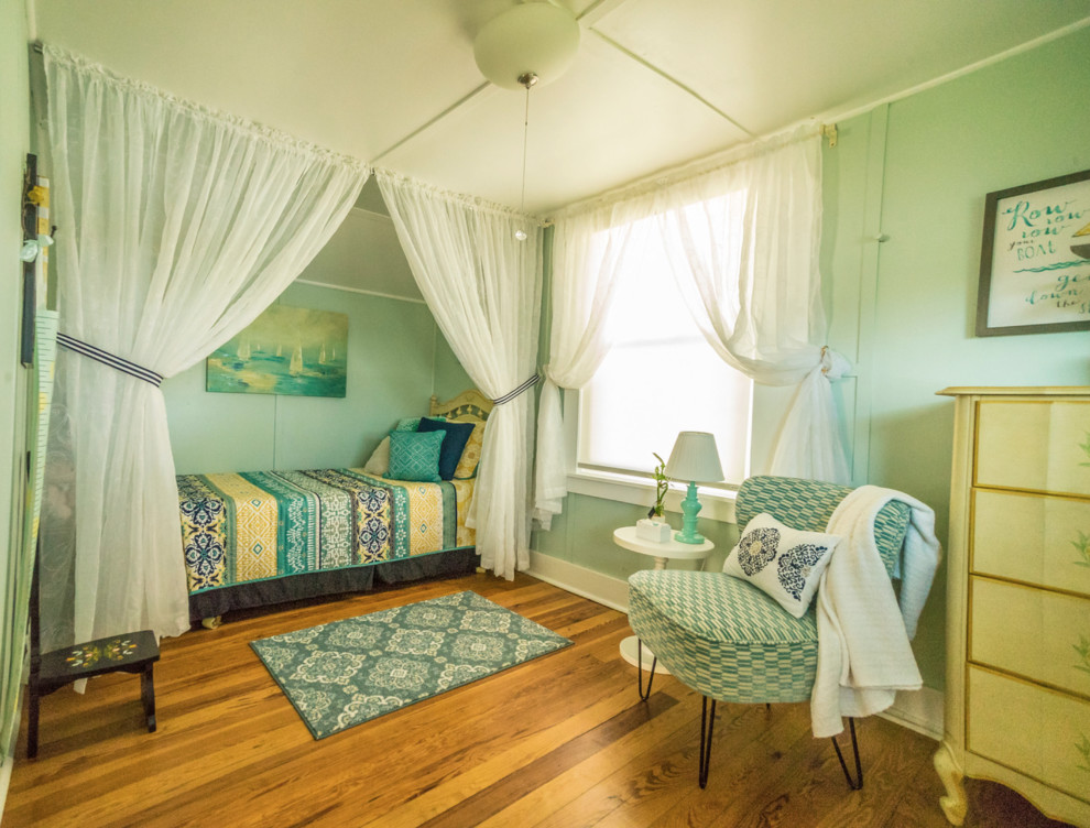 Cette photo montre une petite chambre éclectique avec un mur vert, un sol en bois brun et un sol marron.