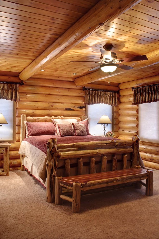 На фото: хозяйская спальня среднего размера в стиле рустика с ковровым покрытием и фасадом камина из камня с
