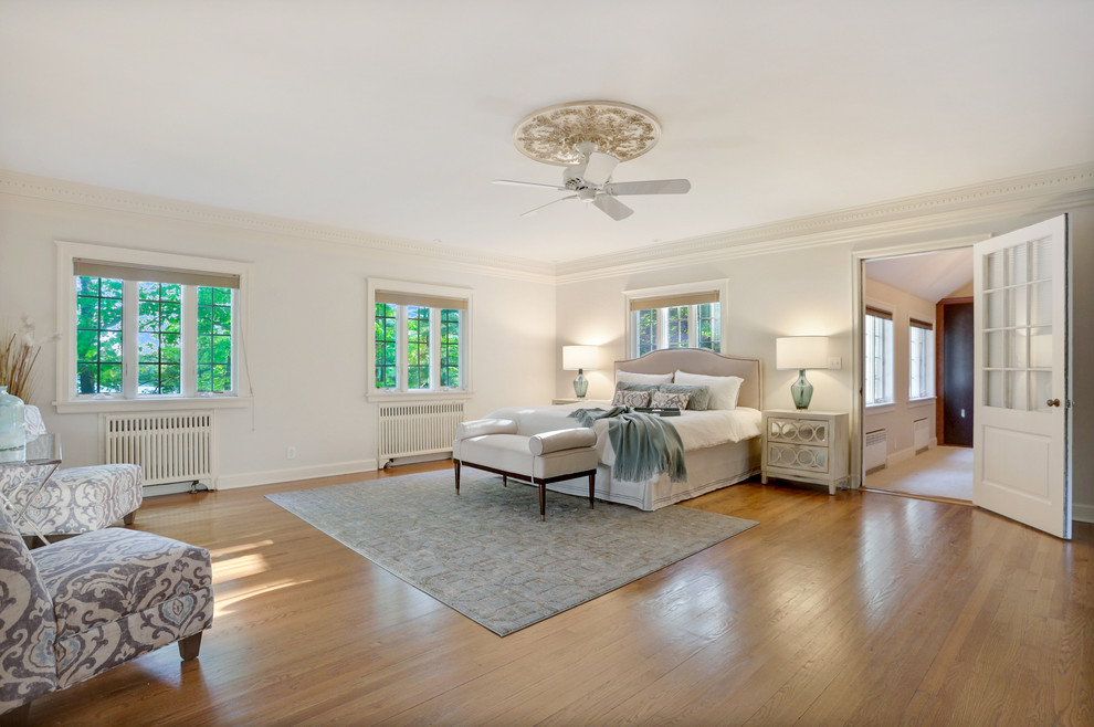 Example of a large transitional master medium tone wood floor bedroom design in New York with gray walls, a standard fireplace and a stone fireplace