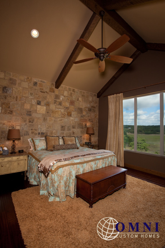 Large rustic master bedroom in Austin with beige walls, dark hardwood flooring and no fireplace.