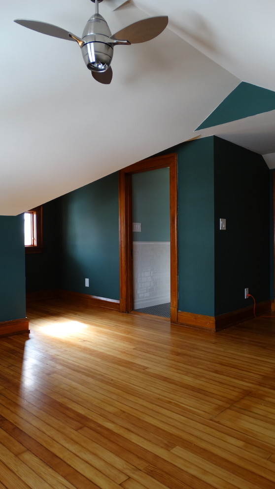 Foto på ett stort amerikanskt gästrum, med gröna väggar och ljust trägolv