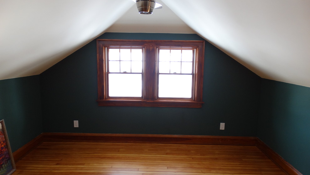 Cette photo montre une grande chambre d'amis craftsman avec un mur vert, parquet clair et aucune cheminée.