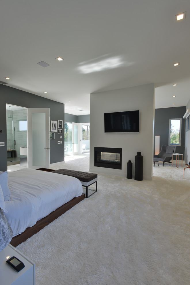 Foto de dormitorio principal moderno grande con paredes grises, moqueta, marco de chimenea de metal y chimenea de doble cara