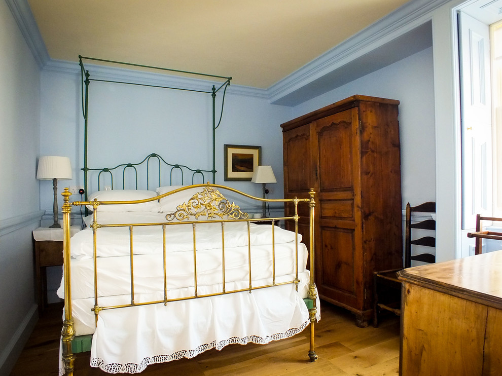 Diseño de habitación de invitados tradicional de tamaño medio sin chimenea con paredes azules y suelo de madera en tonos medios