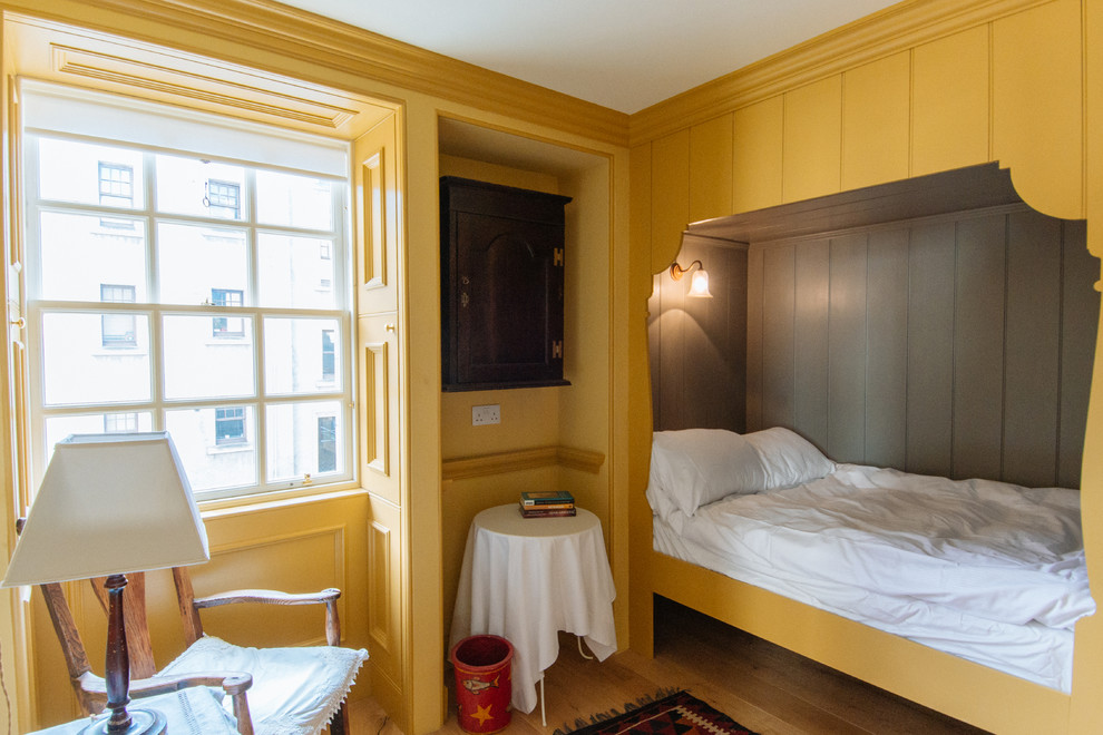 Inspiration pour une chambre d'amis traditionnelle de taille moyenne avec un mur jaune, un sol en bois brun et aucune cheminée.