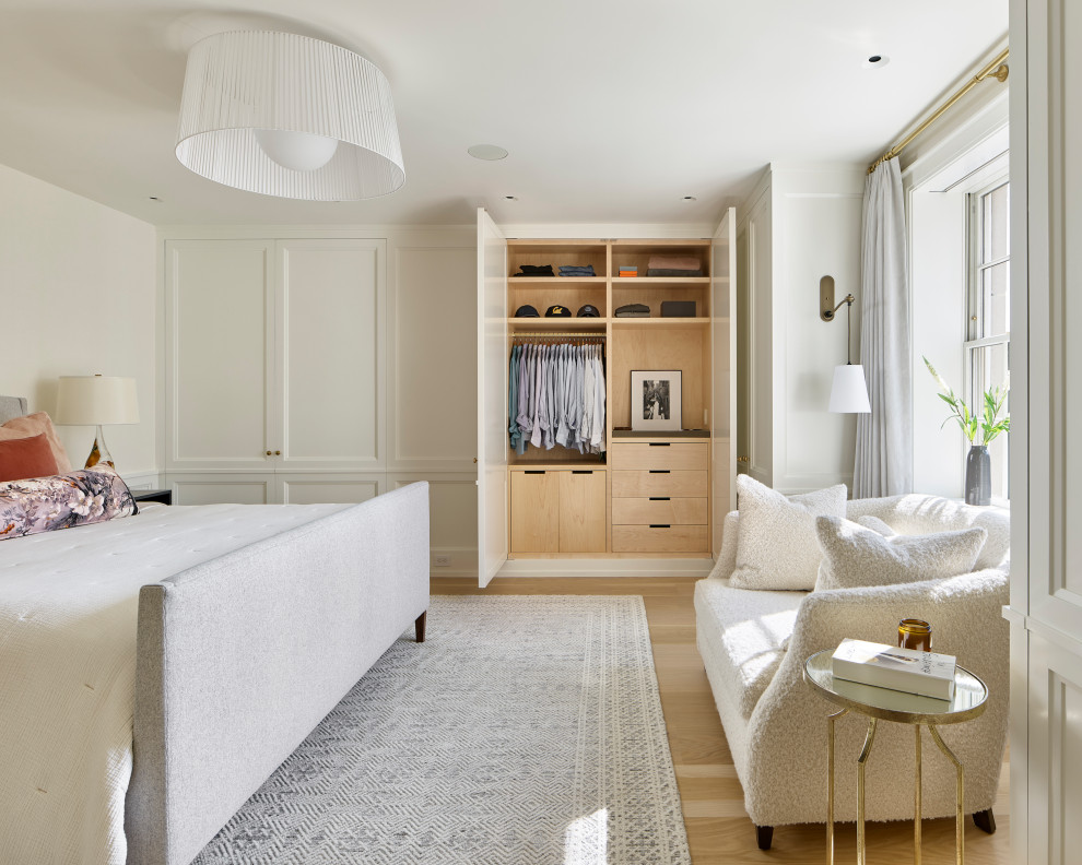 Ispirazione per una camera da letto tradizionale con pareti bianche, parquet chiaro, pavimento beige e boiserie
