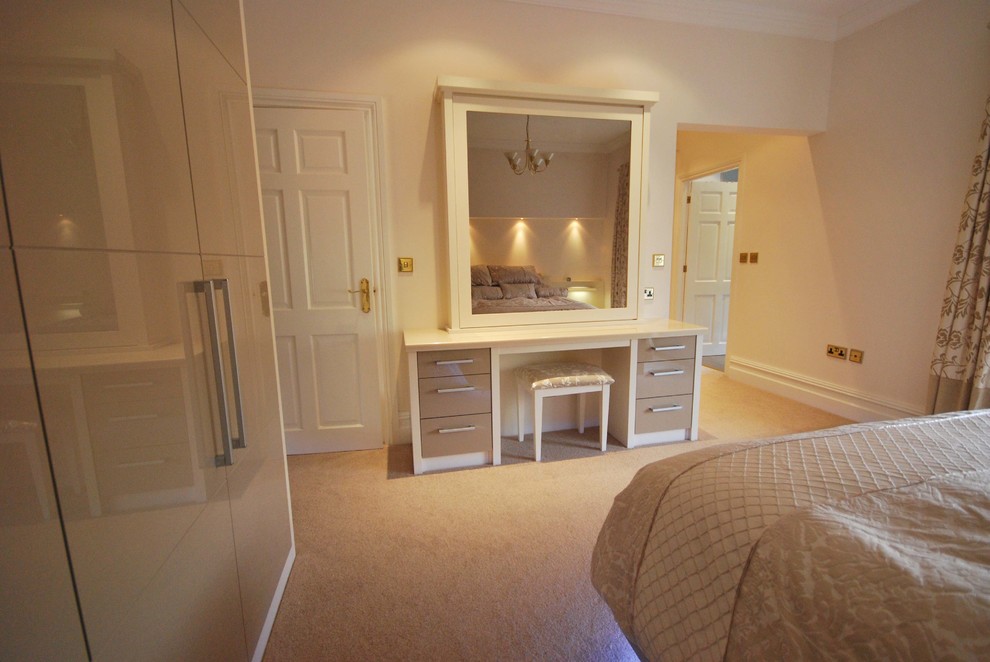 Large contemporary master bedroom in Manchester with beige walls and carpet.