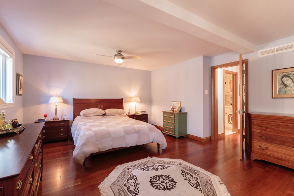 Imagen de dormitorio principal clásico renovado grande con paredes azules y suelo de madera en tonos medios