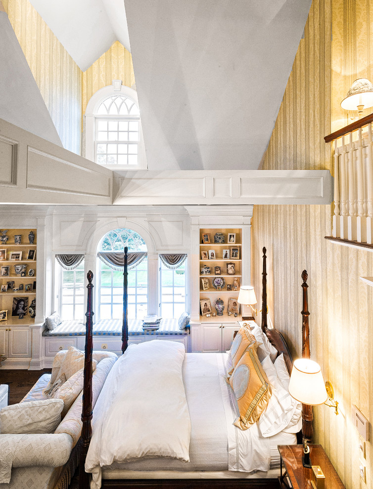 Diseño de dormitorio tipo loft tradicional grande con paredes amarillas y suelo de madera clara