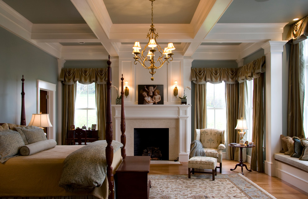 На фото: хозяйская спальня среднего размера в классическом стиле с серыми стенами, светлым паркетным полом, стандартным камином, фасадом камина из штукатурки и коричневым полом с
