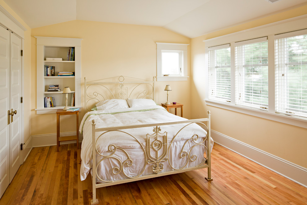 Idéer för mellanstora amerikanska sovrum, med gula väggar och mellanmörkt trägolv